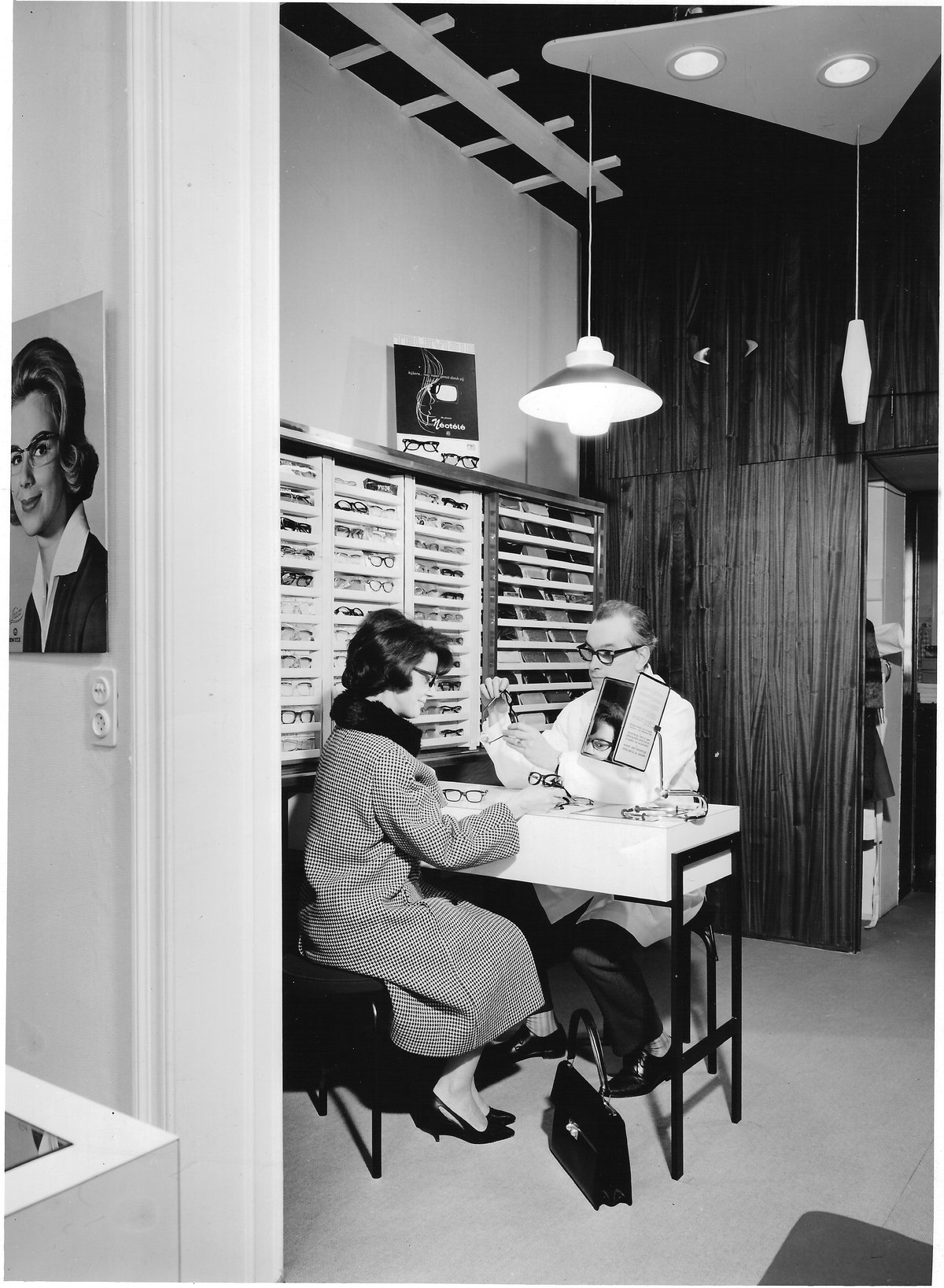 Robert Michils, fondateur de Michils Opticiens en 1955, conseille une cliente dans la boutique